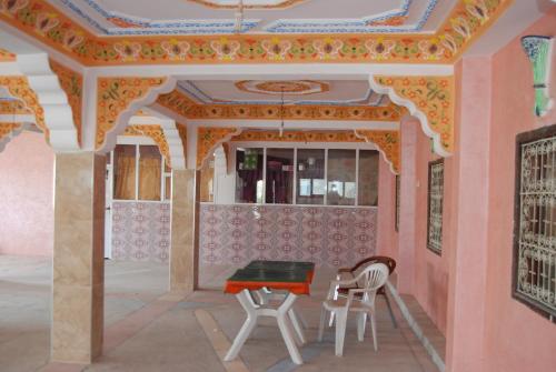 a table and chairs in a room with a ceiling at Auberge Tafilalt Bouzmou Bouzmou in Imilchil