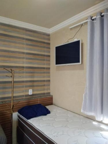 a bedroom with a bed with a television on the wall at Pousada Chalé Morada in Valparaíso de Goiás