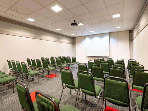 a conference room with green chairs and a white screen at Ibis São Carlos in São Carlos