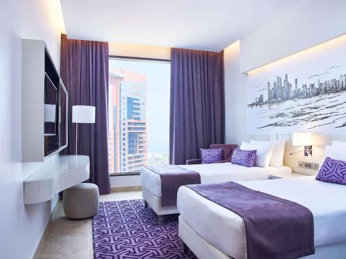 una camera d'albergo con due letti e una grande finestra di Mercure Dubai Barsha Heights Hotel Suites And Apartments a Dubai