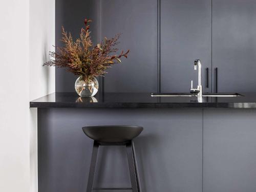 a kitchen counter with a vase with a plant on it at Novotel Melbourne South Wharf in Melbourne