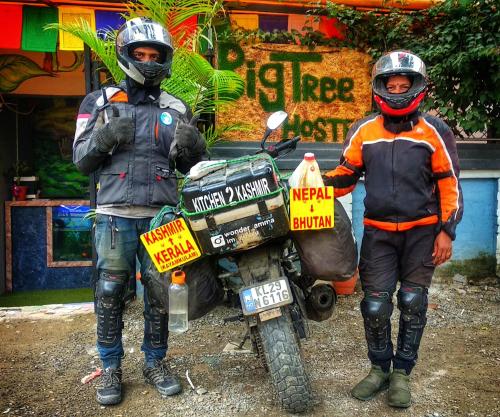 two men wearing helmets standing next to a motorcycle at Big Tree Hostel in Kathmandu
