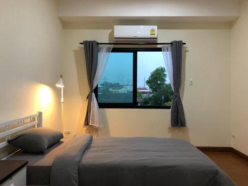 a bedroom with a bed and a window with a laptop at PaperPlane Haiya Nordic House in Chiang Mai