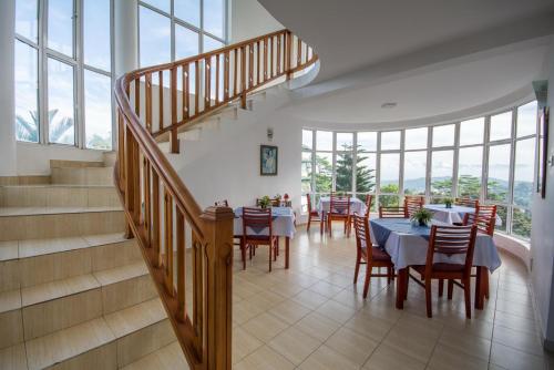 a dining room with tables and chairs and a staircase at Kandyan View Holiday Bungalow free pickup from kandy in Kandy