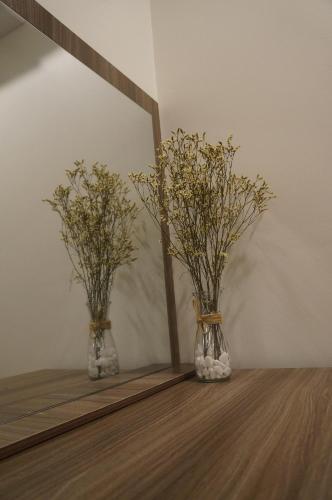 two vases with flowers in them sitting on a table at New Sky Airport Hotel in Noi Bai
