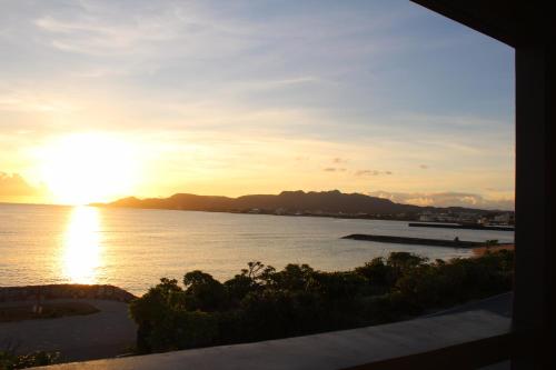 a view of the ocean at sunset from a house at Gate Inn Nago in Nago