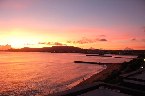 a sunset over the water with a beach at Gate Inn Nago in Nago