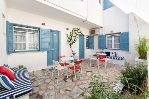 a patio with chairs and a table and blue doors at Fivos Apartments in Aliki