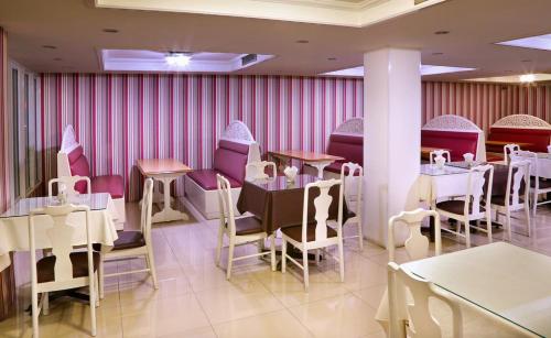 ein Esszimmer mit Tischen und Stühlen und rosafarbenen Wänden in der Unterkunft Highway Hotel in Chiang Mai