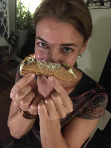 a woman holding a sandwich in front of her face at Casa tipica siciliana patronale home BedandBreakfast TreMetriSoprailCielo Camere con vista, colazione interna in terrazzo panoramico in Caltagirone
