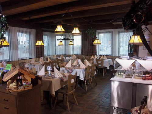 una sala da pranzo con tavoli, sedie e luci di hotel rappen a Baiersbronn
