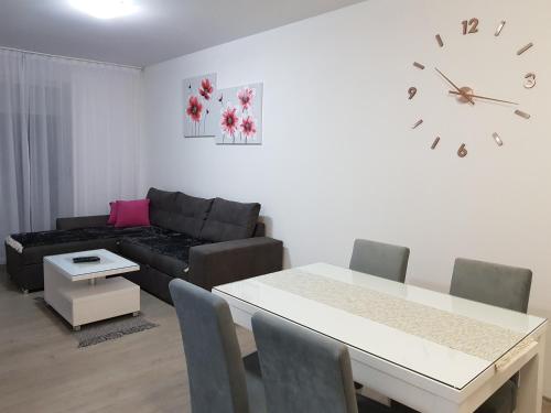 a living room with a couch and a table and a clock at Apartment GEA 18 in Novi Sad