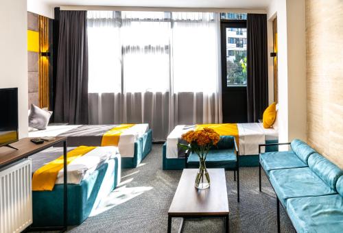 トビリシにあるBG Palace Hotelのベッド2台とソファが備わるホテルルームです。