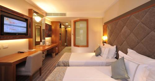 a hotel room with two beds and a desk and a television at Tugcan Hotel in Gaziantep