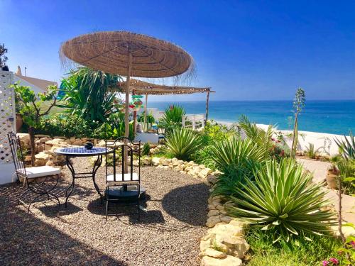une terrasse avec une table et un parasol et l'océan dans l'établissement Villa Jardin De l'Ocean, à Aourir