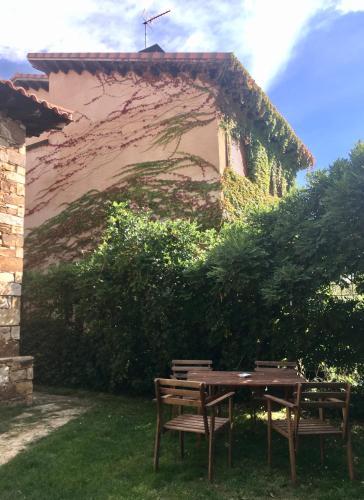 a wooden table and two chairs in front of a building at El Hayuco de Montejo in Montejo de la Sierra