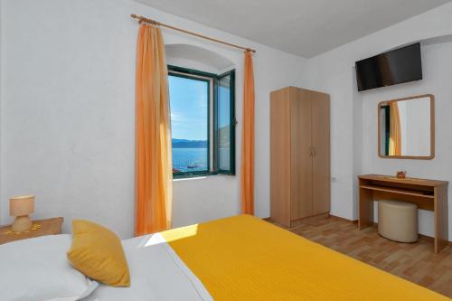 a bedroom with a bed with an orange curtain and a window at Dado A6 Apartments in Igrane