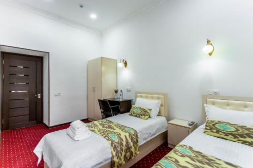 Habitación de hotel con 2 camas y escritorio en Hotel Suzani Samarkand, en Samarkand