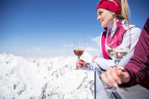 a woman holding a glass of wine in front of a mountain at Glacier Hotel Grawand in Maso Corto