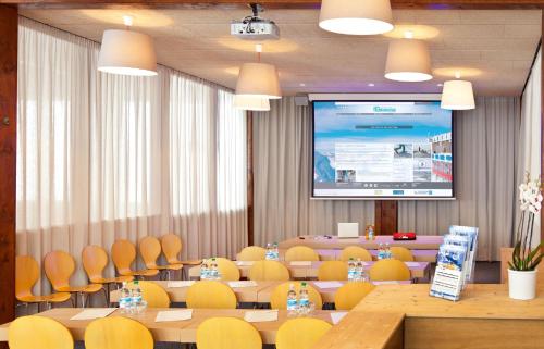 a conference room with tables and chairs and a projection screen at Glacier Hotel Grawand in Maso Corto