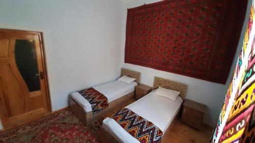 two beds in a room with a door and a rug at "YOQUT HOUSE" guest house in the centre of ancient city in Khiva
