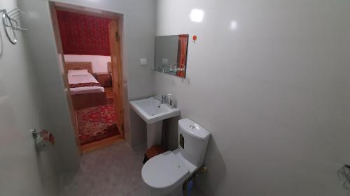 a white bathroom with a toilet and a sink at "YOQUT HOUSE" guest house in the centre of ancient city in Khiva