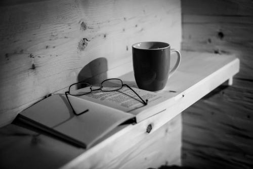 a coffee cup and a book and glasses on a table at Almhuette MeineZeit in Donnersbachwald