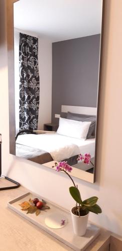 einen Spiegel, der ein Schlafzimmer mit einem Bett reflektiert in der Unterkunft City Vibes Hotel in Sindelfingen