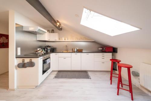 cocina con armarios blancos y taburete rojo en Ferienwohnung EVA en Seekirchen Markt