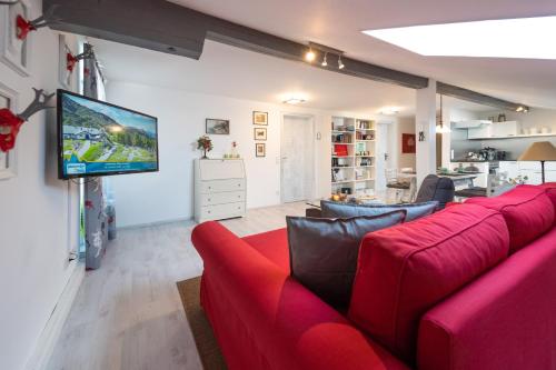 sala de estar con sofá rojo y TV de pantalla plana en Ferienwohnung EVA en Seekirchen Markt