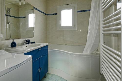 a bathroom with a tub and a sink and a bath tubermottermott at Les Coquillages in La Guérinière