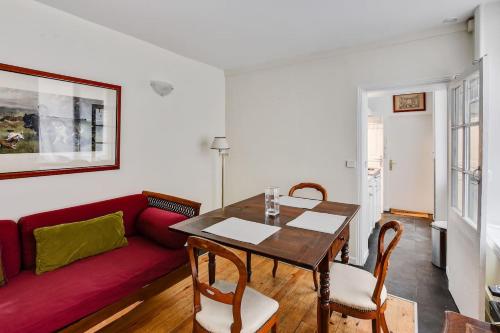 un salon avec une table et un canapé rouge dans l'établissement Unit 008 Saint Germain des Pres (Bac rdc), à Paris