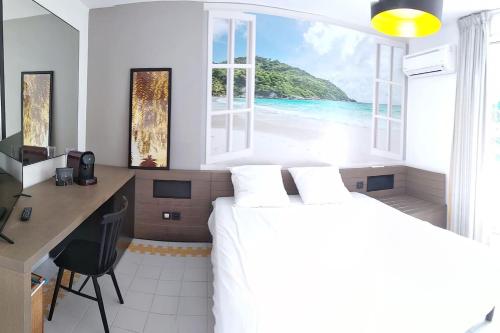 Un dormitorio con dos camas y un escritorio y una ventana. en Studio avec GRANDE PISCINE, PLAGE Vanille Caraïbes, en Saint-François