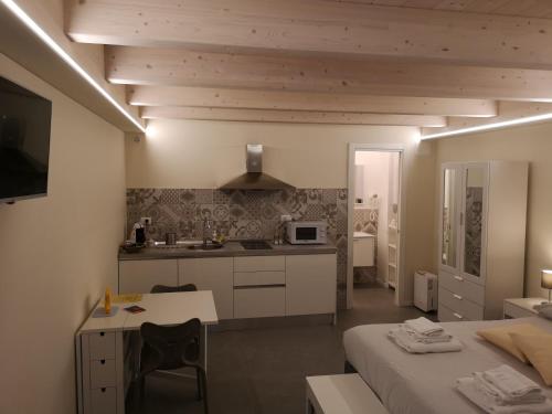 Vico-Letto studio apartment في غواردياغريلي: غرفة مع مطبخ ومكتب في غرفة