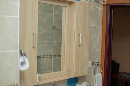 a wooden cabinet with a glass door in a bathroom at Bays Lodge, Accra in Accra