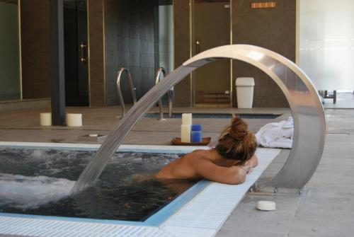 a woman laying in a bath tub in a swimming pool at Mas Ses Vinyes - Adults Only in Begur