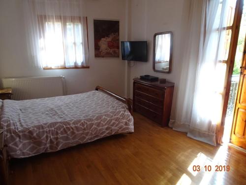 a bedroom with a bed and a dresser and a television at Vitina's little house in Vytina