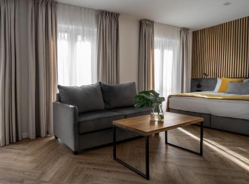 a hotel room with a bed and a couch and a table at Jono kalnelis Apartments in Klaipėda