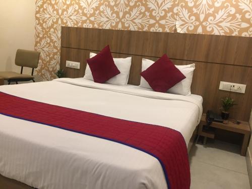a bedroom with a large bed with red pillows at Hotel Imperial in Vasai