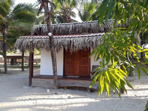 a small hut on the beach with a thatched roof at Chalé Morada da Fê in Praia de Moitas
