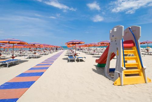 a beach with chairs and umbrellas and a slide at Country House Il Cascinale in Colonnella