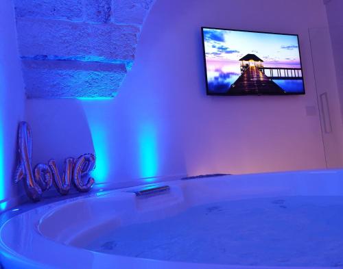 a bathroom with a tub with a tv on the wall at Christian's Suites & Spa in Fasano