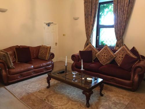 a living room with two leather couches and a coffee table at Bridge Farm Hotel in Leeds