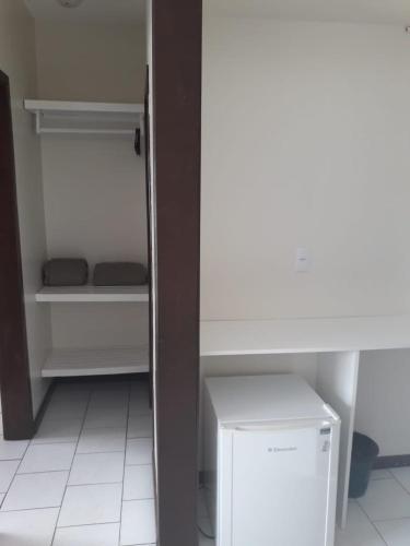 a room with a white refrigerator and a table at HsHotelaria - Filial Bombinhas in Bombinhas