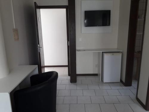 a room with a television and a table and a chair at HsHotelaria - Filial Bombinhas in Bombinhas