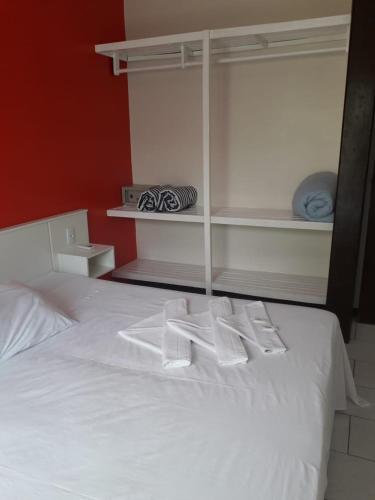 a bedroom with a white bed with white shelves at HsHotelaria - Filial Bombinhas in Bombinhas