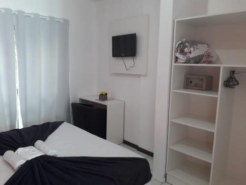 a bedroom with a bed and a tv and shelves at HsHotelaria - Filial Bombinhas in Bombinhas