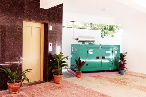 una máquina verde sentada fuera de un edificio con plantas en Jasmine park, en Chennai