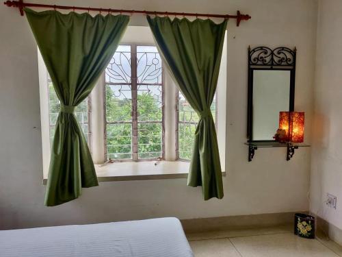 a bedroom with a window with green curtains at Preyoshi in Bolpur