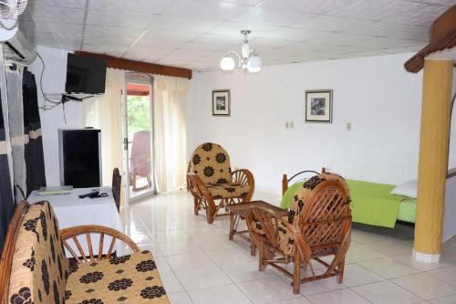 a living room with wicker chairs and a tv at Hotel Valle Verde in Valle de Anton